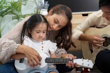 Bir annenin kızına ukulele çalması için rehberlik ettiği yaratıcı ve sevgi dolu bir an..