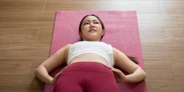 Bu görüntü, evde yoga yaparken rahatlama tekniklerine başvuran yansıtıcı poziyonda bir kadını yakalar..