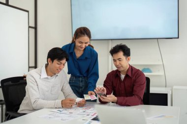 İşbirlikçi ortam, üç UX UI tasarımcısı tasarım kartları ve planlarını değerlendirir, projelerini geliştirmek ve işlevselliklerini geliştirmek için takım çalışmasını teşvik eder.