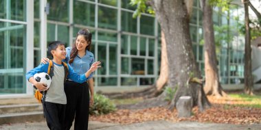 Bir ebeveyn ve çocuk okuldan sonra yan yana yürür, gülümseme ve sohbet paylaşır, iletişimin ve aile zamanının önemini vurgular.