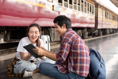 Genç bir çift, tren istasyonundan sonraki yolculukları için heyecanlı bir tablet üzerinde seyahat planlarını incelerken birlikte keyifli bir anın tadını çıkarıyor..
