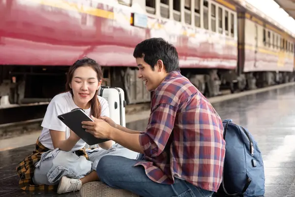 Genç bir çift, tren istasyonundan sonraki yolculukları için heyecanlı bir tablet üzerinde seyahat planlarını incelerken birlikte keyifli bir anın tadını çıkarıyor..