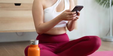 Bir sağlık meraklısı, sakinleştirici yoga rutininden zevk aldıktan sonra telefonuna su verip bağlantı kurar..