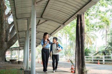 Çocuk ve akıl hocası ağaçlık bir yolda yürürler, hikayeler ve kahkahalar paylaşırlar, okul gününün bitişini kutlarlar ve futbol gibi eğlenceli hobiler edinirler..