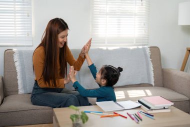 Bir anne ve kızı eğlenceli bir el çırpma oyunu sırasında kahkahalarını paylaşıyor, eğlenceli etkileşimler yoluyla neşe ve bağlantıyı teşvik ediyorlar..