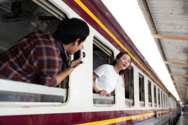 Bir adam hevesle ortağının fotoğrafını çeker. O da neşeyle tren penceresinden sarkar. Macera ruhunu ve doğallığını somutlaştırır..