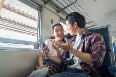 Genç bir çift trende neşeli bir sohbete dalıyor, kahkahalarla dolu neşeli bir anı yakalıyorlar. Bağlantıları seyahat deneyimini güçlendirir..