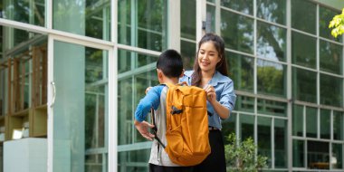 Bir anne oğluna sırt çantasıyla yardım eder, okula hazır olmasını sağlar. Bu sahne ebeveynliğin ve çocukluk hazırlığının besleyici yönünü temsil eder..