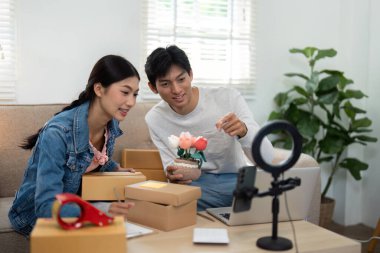 Nişanlı bir çift çalışma alanlarını canlı yayın oturumuna hazırlıyor, çevrimiçi seyircileriyle bağlantı kurmaya ve yenilikçi ürünler sergilemeye hazır..