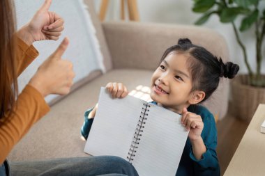 Kız gururla annesine defterini sunar, cesaret verici geri bildirim alır ve yaptığı iş için şükreder..