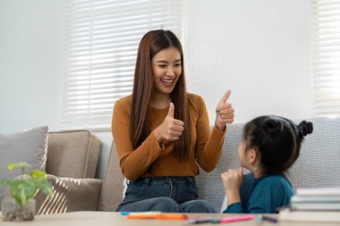 Bir kadın, öğrenme seansı sırasında genç bir kızı mutlu bir şekilde cesaretlendirir, kendine güveni artıran olumlu etkileşimler gösterir..