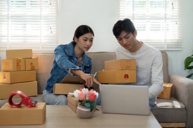 Girişimcilerden oluşan dinamik bir ekip, e-ticaret işlerinde işbirliği yapan bir çift, bir ev ortamında strateji ve lojistik tartışmaları yaparken paketleri ayırıyorlar..