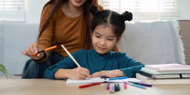 Neşeli bir çalışma seansında, bir kız destekleyici bir yetişkin olarak onu cesaretlendirir. Bu ayar işbirliğiyle dolu olumlu bir öğrenme deneyimini örneklendirir..