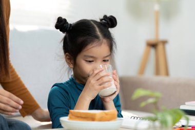 Çalışmaya ara veren genç bir kız, bir bardak sütle kendini yeniliyor, beslenme ve akademik çalışmanın dengesini destekliyor..