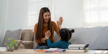 İnteraktif aktiviteler sırasında bir kadın ve çocuğun beşlik çaktığı, öğrenmenin eğlencesini vurguladığı neşeli bir an..