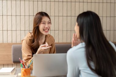Öğrenciler farklı konuları incelerken, öğrenmede işbirliğinin önemini vurgulayan iki öğrenci arasında keyifli bir alışveriş..