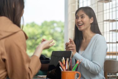 İki üniversite öğrencisi, kitap ve notlarla dolu, takım çalışması ve arkadaşlığın sergilendiği samimi bir ortamda çalışırken fikir ve çözümleri paylaşıyor..