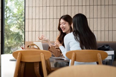 İki genç kadın hararetli bir sohbete girişiyor, akademik görüşlerini paylaşıyor ve üniversite ortamında görevleri üzerinde birlikte çalışıyorlar..