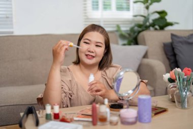 Rahat bir atmosferde, bir kadın güzellik yağını coşkuyla inceler, cilt bakımına ve güzellik alışkanlıklarına olan tutkusunu gösterir..