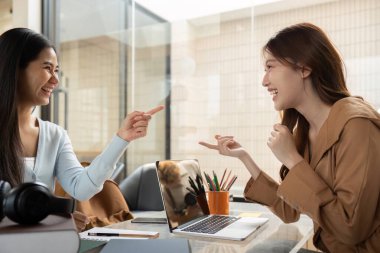 Parlak bir çalışma alanında, iki öğrenci çalışmalarını tartışırken aynı kahkahayı paylaşıyor, birlikte öğrenmenin zevkini vurguluyorlar..