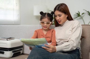 Heyecan verici bir yolculuğa hazırlanırken, anne ve kızı bir harita üzerinde keşif anlarını paylaşıyor ve olası varış noktalarını tartışıyor..