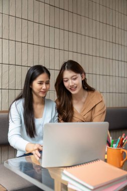 İki arkadaş notları değerlendiriyor ve bir masada oturup, takım çalışması ve akademik odak noktalarını gözler önüne sererken öğrenim materyallerini tartışıyorlar..