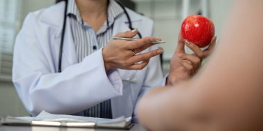 Bir doktor diyet seçimlerinde dengenin önemini hastaya hem tatlı hem de sağlıklı bir elma sunarak vurgular..