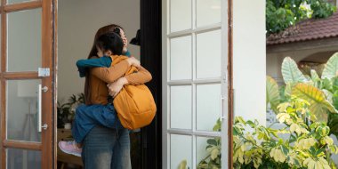 Bir annenin okuldan sonra kızını sıcak bir kucaklamayla kucağına alıp sevgi ve mutlulukla dolu aile anlarını resmettiği neşeli bir sahne..