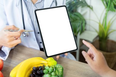 Bir beslenme uzmanı, renkli meyvelerin yanı sıra sağlıklı gıda seçeneklerini tartışmak için hastayı görsel olarak meşgul eden bir tablet üzerinde yemek planlamasını gösterir..