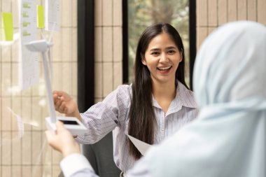 Kadın burada fikirlerle uğulduyor, ESG stratejilerini ve sürdürülebilirlik tedbirlerini partnerine vurguluyor, sürdürülebilir uygulamaları destekliyor.