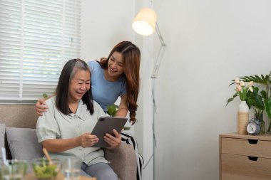 Anne ve kızı, bir tablete bakıp, aile bağlarını geliştirmenin bir yolu olarak teknolojiyi kutlarken, keyifli bir anı paylaşıyorlar..