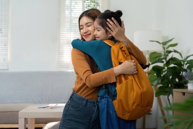 Sevgi dolu bir anne, okula döndüğü ilk gün için heyecanlı olan kızını kucaklıyor. Görüntü, aile desteğinin ve yeni başlangıçların neşesini yakalıyor..