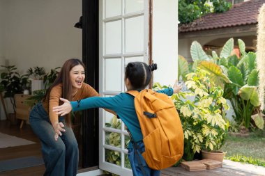 Küçük bir kız okuldan döndükten sonra annesini sıcak bir kucaklama ile karşılar. Bu an, aile birleşmelerinin derin duygusal bağını ve neşesini yansıtıyor..