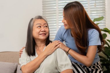 Gülümsemelerini ve rahatlıklarını paylaştıkları bir anne ve kız arasındaki sevgi dolu etkileşim samimi bir ortamda onların destekleyici ilişkilerini vurguluyor..