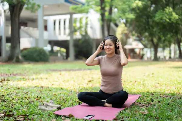 Verimli bir ortamda, bir kadın rahat bir şekilde oturur, müzikle meditasyondan zevk alır, sağlık rutininin bir parçası olarak farkındalığı geliştirir..