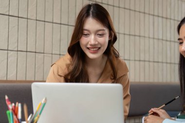 Bir üniversite öğrencisi, akranlarıyla çalışırken, akademik uğraşlardaki arkadaşlıkları vurgulayarak, bir neşe ve keşif anını paylaşır..