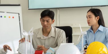 Modern bir ofiste, iki profesyonel yenilenebilir enerji modelleri, sürdürülebilirlik ve çevre dostu uygulamaların vurgulanması, eğitim ve kurumsal ortamlar için ideal.