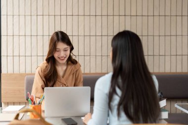 Çalışmalarla meşgul olan iki arkadaş, samimi bir kafe atmosferinde notlar ve stratejileri tartışarak etkin bir şekilde işbirliği yapıyorlar..