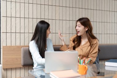 İki öğrenci bir proje üzerinde çalışırken gülümsüyor ve şakalaşıyorlar. Akademide arkadaşlığın sevincini gösteriyorlar..