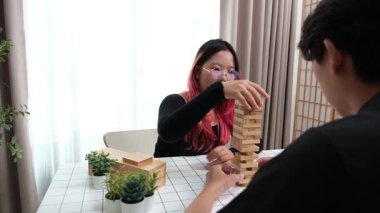 Gülen çift oturma odalarında ahşap oyunlar oynayarak eğleniyor. Sevgi kavramı, rahatlama ve evdeki eğlenceli anlarda bağlanma..