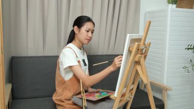 Sevimli genç kız evde resim çizerek ve boyayarak en sevdiği aktiviteyle yaratıcılığını ifade ediyor. Çocukluk hayal gücü, sanat ve oyun yoluyla öğrenme kavramı.