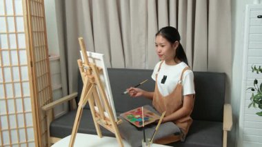 Sevimli genç kız evde resim çizerek ve boyayarak en sevdiği aktiviteyle yaratıcılığını ifade ediyor. Çocukluk hayal gücü, sanat ve oyun yoluyla öğrenme kavramı.