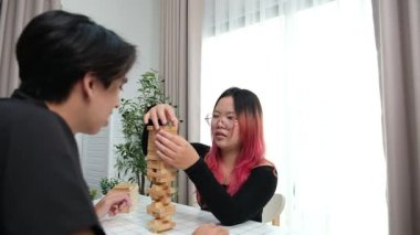 Gülen çift oturma odalarında ahşap oyunlar oynayarak eğleniyor. Sevgi kavramı, rahatlama ve evdeki eğlenceli anlarda bağlanma..