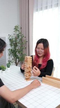 Gülen çift oturma odalarında ahşap oyunlar oynayarak eğleniyor. Sevgi kavramı, rahatlama ve evdeki eğlenceli anlarda bağlanma..