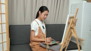 Sevimli genç kız evde resim çizerek ve boyayarak en sevdiği aktiviteyle yaratıcılığını ifade ediyor. Çocukluk hayal gücü, sanat ve oyun yoluyla öğrenme kavramı.