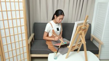 Sevimli genç kız evde resim çizerek ve boyayarak en sevdiği aktiviteyle yaratıcılığını ifade ediyor. Çocukluk hayal gücü, sanat ve oyun yoluyla öğrenme kavramı.