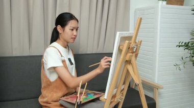 Sevimli genç kız evde resim çizerek ve boyayarak en sevdiği aktiviteyle yaratıcılığını ifade ediyor. Çocukluk hayal gücü, sanat ve oyun yoluyla öğrenme kavramı.