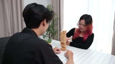 Gülen çift oturma odalarında ahşap oyunlar oynayarak eğleniyor. Sevgi kavramı, rahatlama ve evdeki eğlenceli anlarda bağlanma..