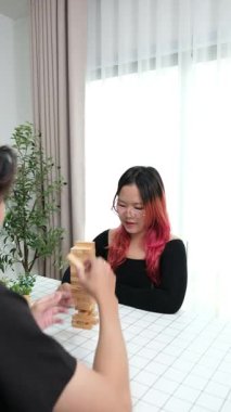 Gülen çift oturma odalarında ahşap oyunlar oynayarak eğleniyor. Sevgi kavramı, rahatlama ve evdeki eğlenceli anlarda bağlanma..