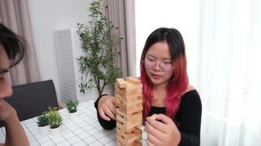 Gülen çift oturma odalarında ahşap oyunlar oynayarak eğleniyor. Sevgi kavramı, rahatlama ve evdeki eğlenceli anlarda bağlanma..